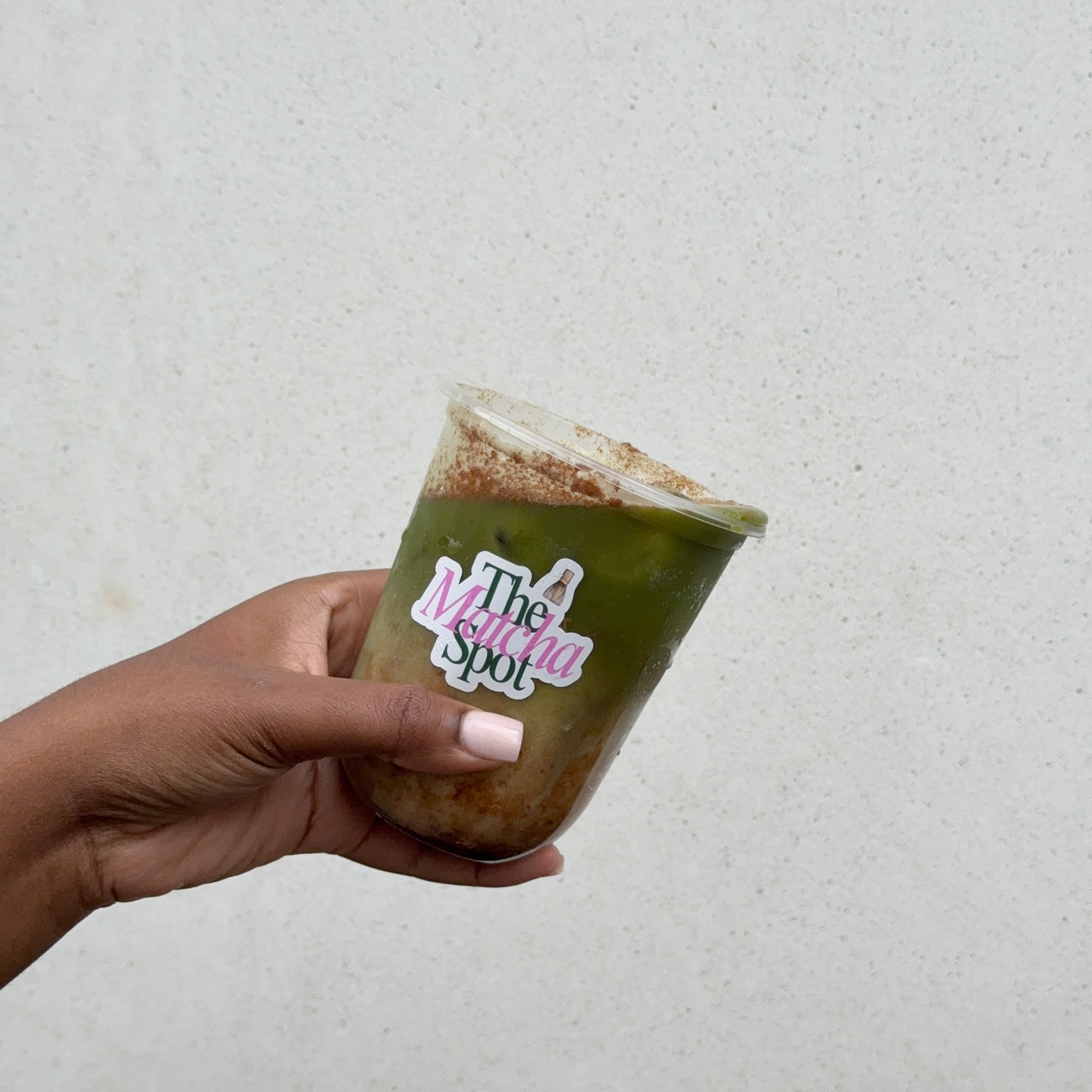 Hand holding a signature iced drink from The Matcha Spot